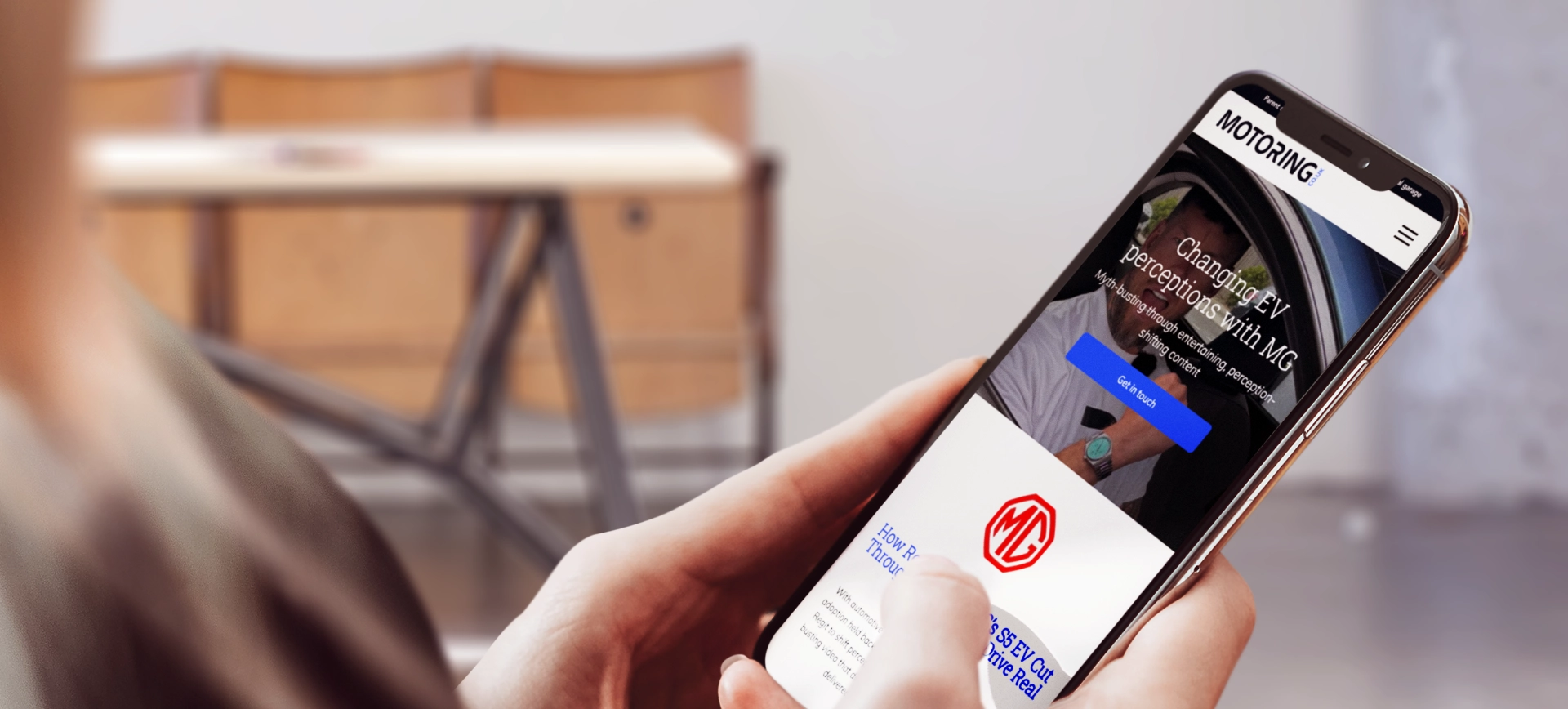Motoring site on a phone held over a desk